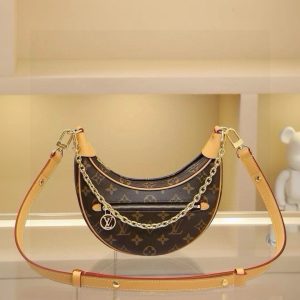 The Croissant handbag, a signature piece from Nicolas Ghesquière's heritage archives, is reimagined as the Loop demi-lune bag for the 2022 Pre-Spring collection. Its compact silhouette follows the body's natural movement, featuring a front zippered pocket with a circular zipper pull. The chain and leather shoulder strap offer versatile carrying options for shoulder or crossbody wear. Dimensions: 23 x 13 x 6 cm.